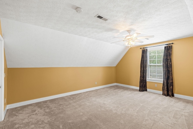 additional living space with a textured ceiling, ceiling fan, lofted ceiling, and light carpet