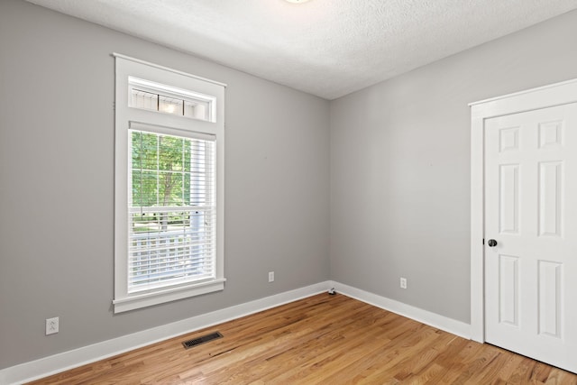 unfurnished room featuring wood-type flooring and a textured ceiling