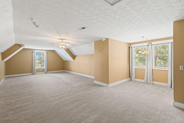 additional living space with ceiling fan, a textured ceiling, light carpet, and vaulted ceiling