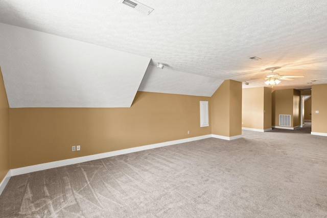 additional living space featuring a textured ceiling, carpet floors, vaulted ceiling, and ceiling fan