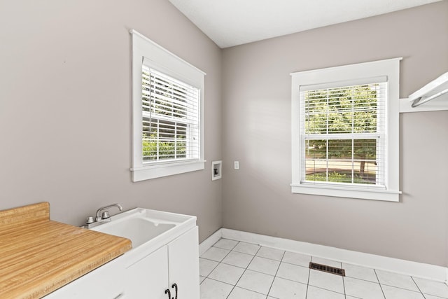 laundry area with cabinets, washer hookup, light tile patterned floors, and plenty of natural light