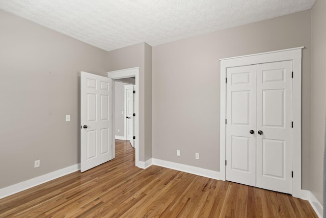 unfurnished bedroom with a closet, a textured ceiling, and light hardwood / wood-style flooring