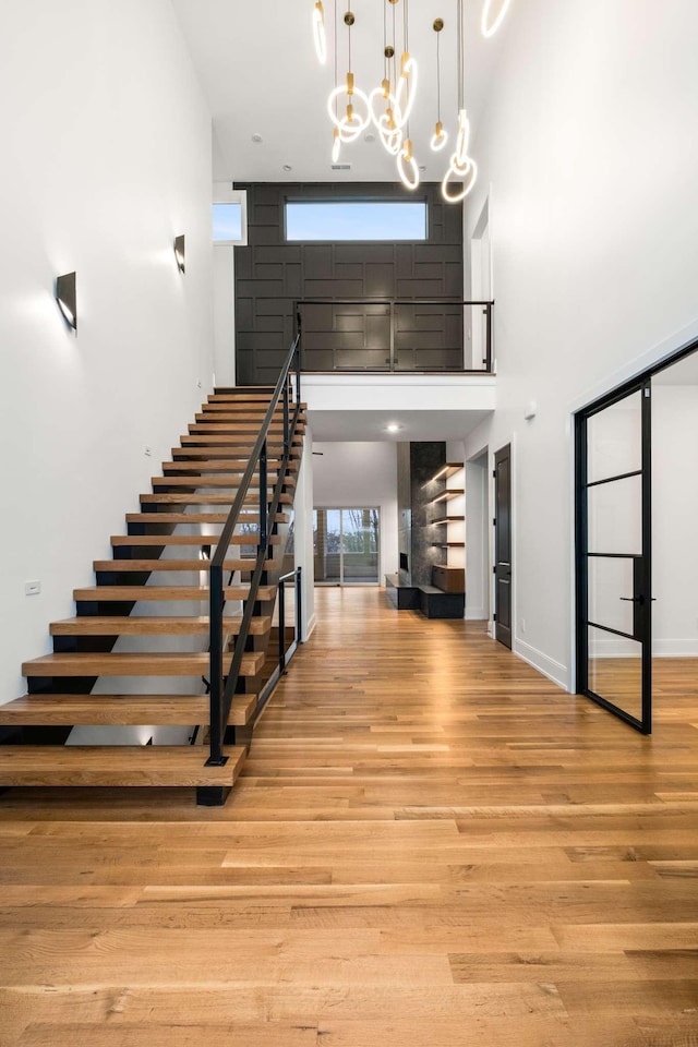 foyer featuring a notable chandelier, light hardwood / wood-style floors, and a towering ceiling