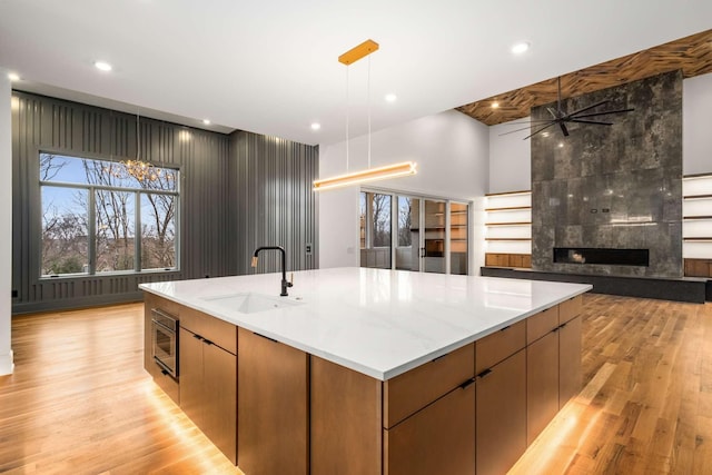 kitchen with ceiling fan, sink, pendant lighting, a spacious island, and light hardwood / wood-style floors