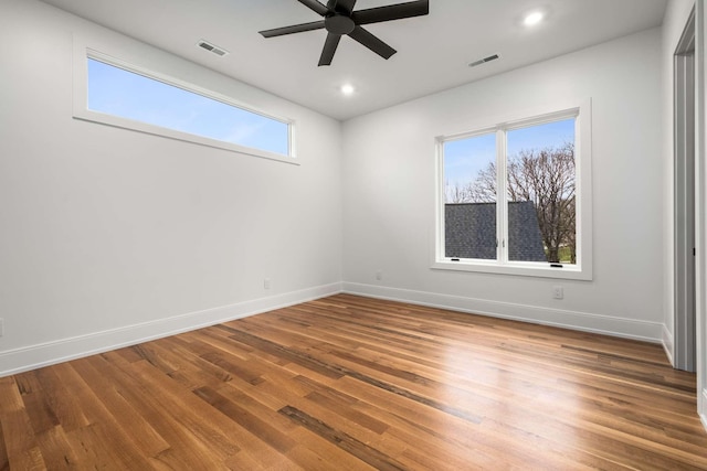 empty room featuring plenty of natural light, ceiling fan, and wood-type flooring