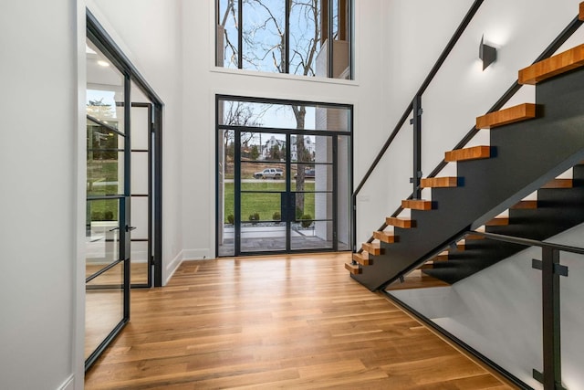 foyer featuring light wood-type flooring, french doors, and a towering ceiling