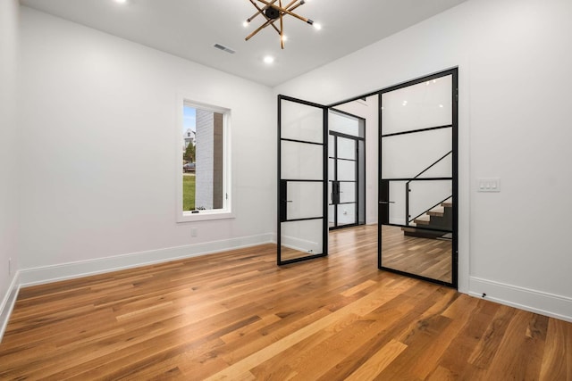 unfurnished bedroom featuring a chandelier and light hardwood / wood-style flooring