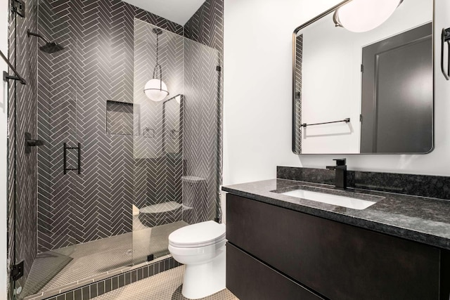 bathroom with tile patterned flooring, vanity, toilet, and tiled shower