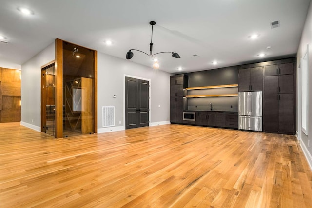 unfurnished living room with light hardwood / wood-style floors and sink