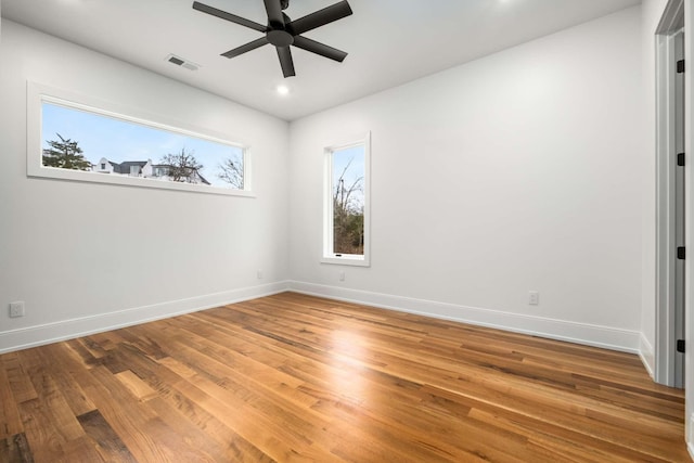 empty room with ceiling fan, plenty of natural light, and wood-type flooring