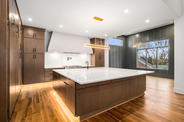 kitchen featuring pendant lighting, a spacious island, light wood-type flooring, and custom exhaust hood