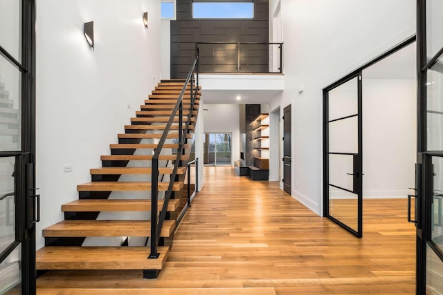 foyer entrance with a towering ceiling and light hardwood / wood-style flooring