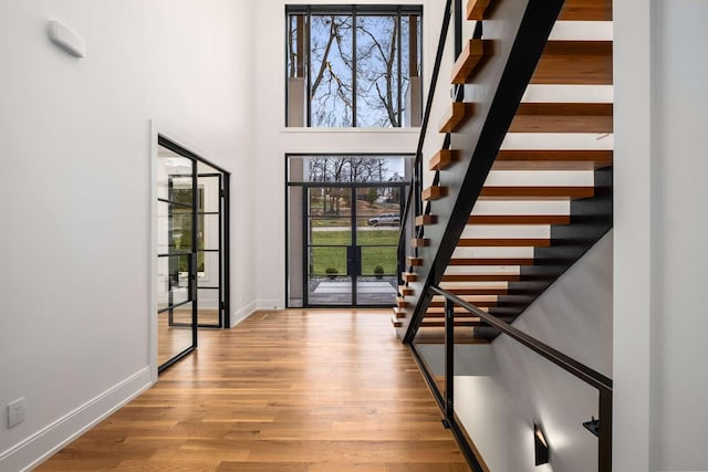 entryway with beam ceiling, a towering ceiling, and light hardwood / wood-style floors