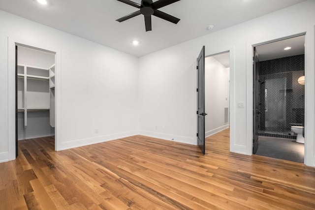 unfurnished bedroom featuring a walk in closet, ceiling fan, hardwood / wood-style floors, and ensuite bath