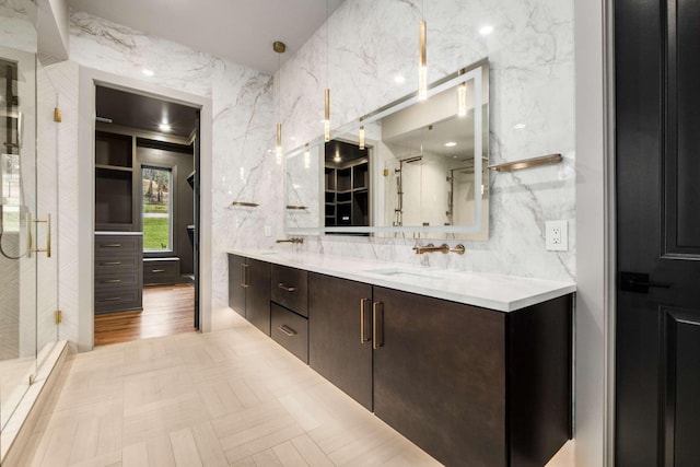 bathroom with vanity, a shower with shower door, and tile walls