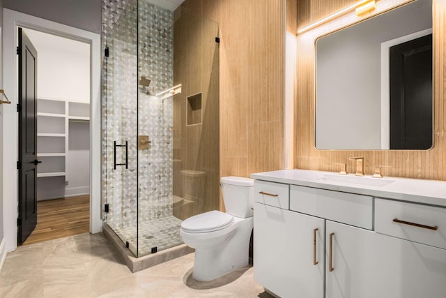 bathroom with hardwood / wood-style flooring, a shower with door, vanity, and toilet