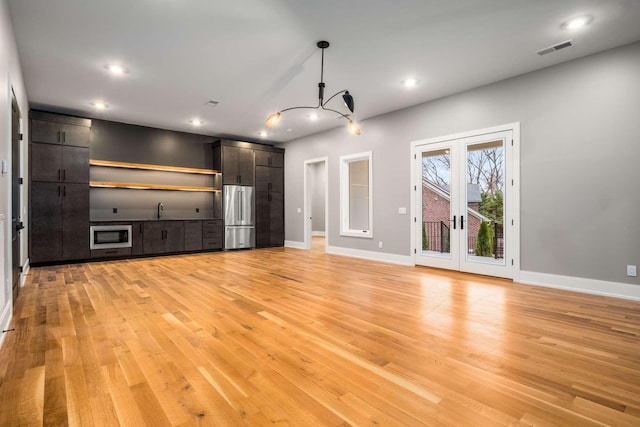 unfurnished living room featuring french doors, light hardwood / wood-style floors, and sink