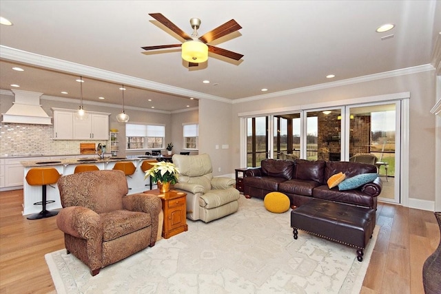 living room with light wood-type flooring, ornamental molding, and a wealth of natural light