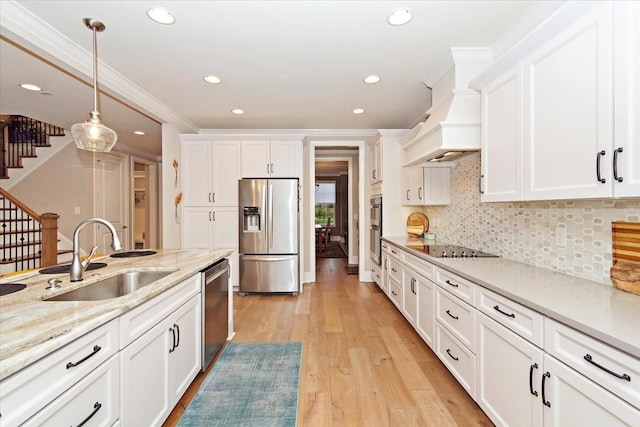 kitchen featuring sink, hanging light fixtures, light hardwood / wood-style flooring, white cabinets, and appliances with stainless steel finishes