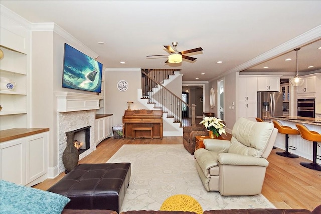 living room featuring a fireplace, light hardwood / wood-style floors, crown molding, and ceiling fan