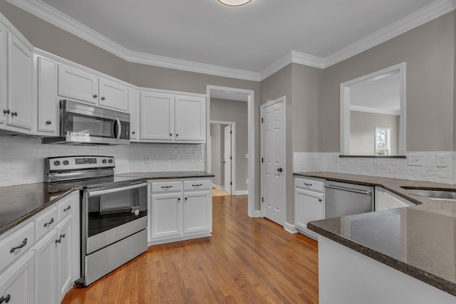 kitchen featuring white cabinetry, tasteful backsplash, light hardwood / wood-style flooring, appliances with stainless steel finishes, and ornamental molding