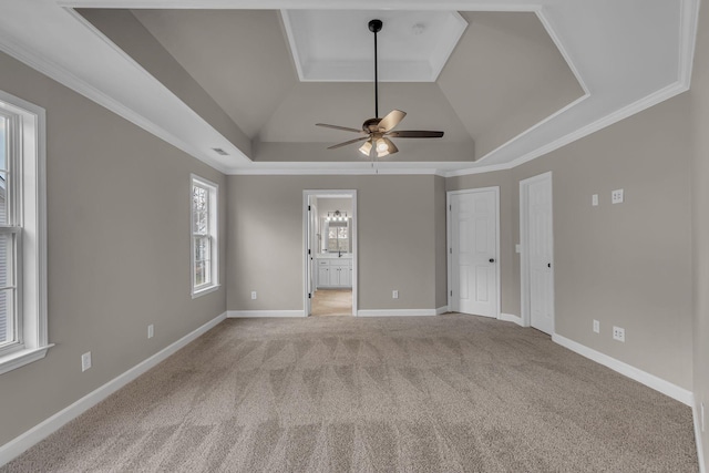 interior space with a tray ceiling, ceiling fan, ornamental molding, and light colored carpet