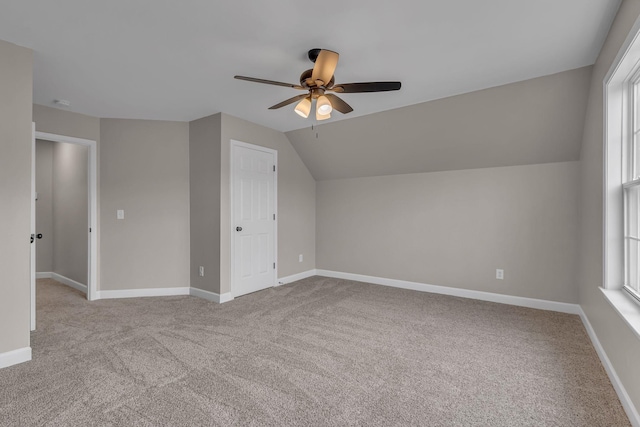 additional living space featuring light colored carpet, plenty of natural light, and lofted ceiling