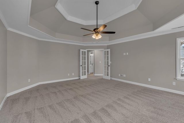 carpeted spare room featuring a tray ceiling, crown molding, french doors, and ceiling fan