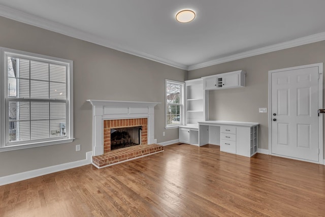 unfurnished living room featuring a brick fireplace, light hardwood / wood-style flooring, and crown molding