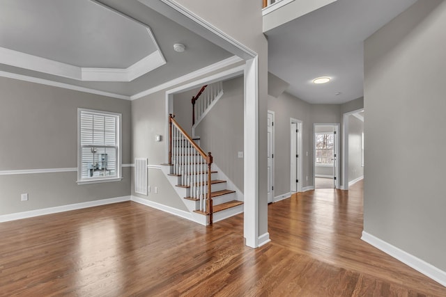 interior space with a raised ceiling, crown molding, and hardwood / wood-style flooring