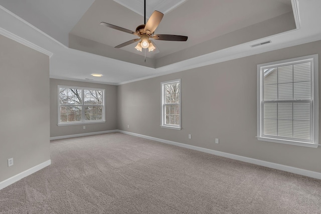 carpeted empty room with ceiling fan, a raised ceiling, and crown molding