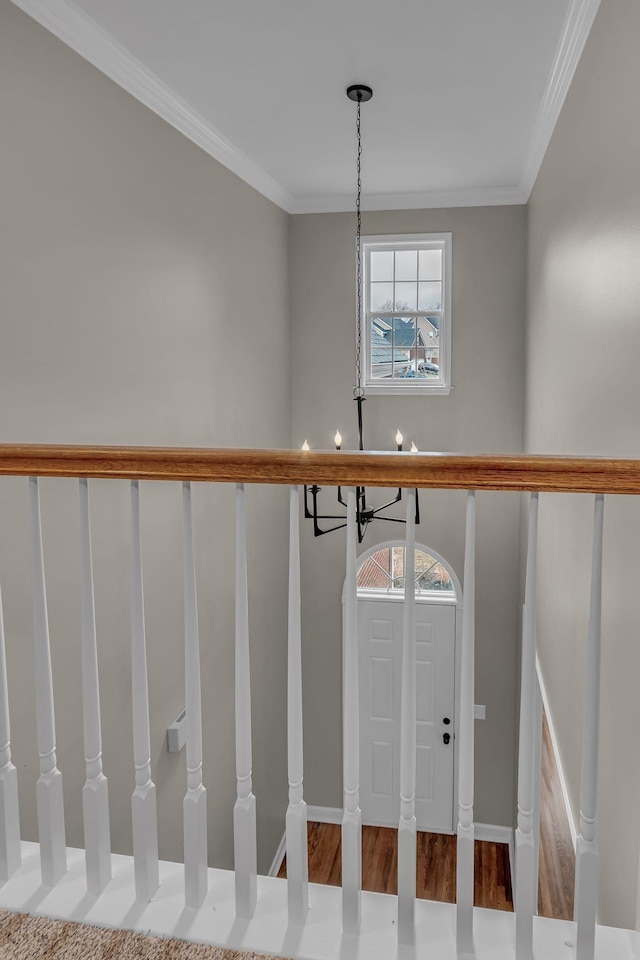 stairs with ornamental molding, plenty of natural light, and a notable chandelier