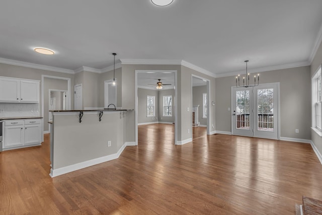 kitchen featuring decorative light fixtures, white cabinetry, ceiling fan with notable chandelier, and light hardwood / wood-style flooring