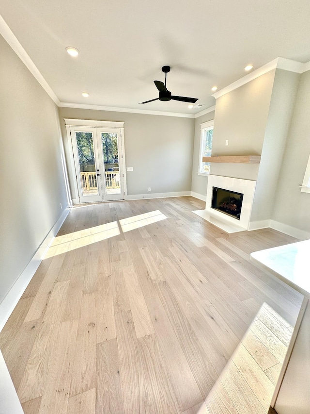 unfurnished living room with ornamental molding, ceiling fan, light wood-type flooring, and french doors