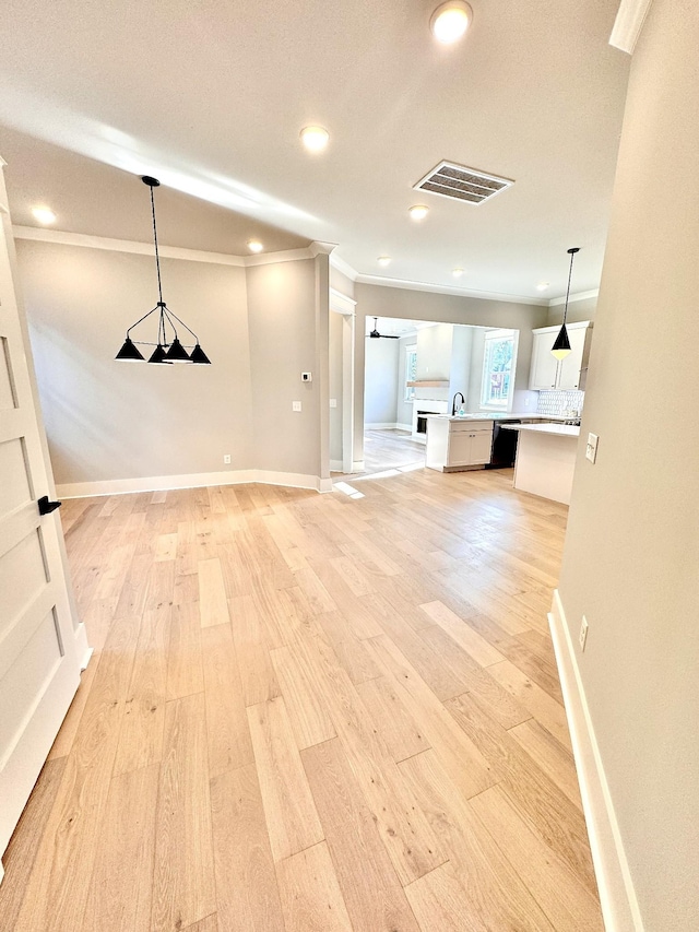 unfurnished living room with light hardwood / wood-style floors, crown molding, and sink