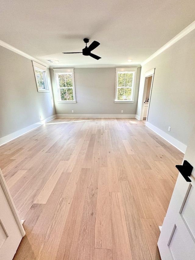 empty room with crown molding, plenty of natural light, ceiling fan, and light hardwood / wood-style floors