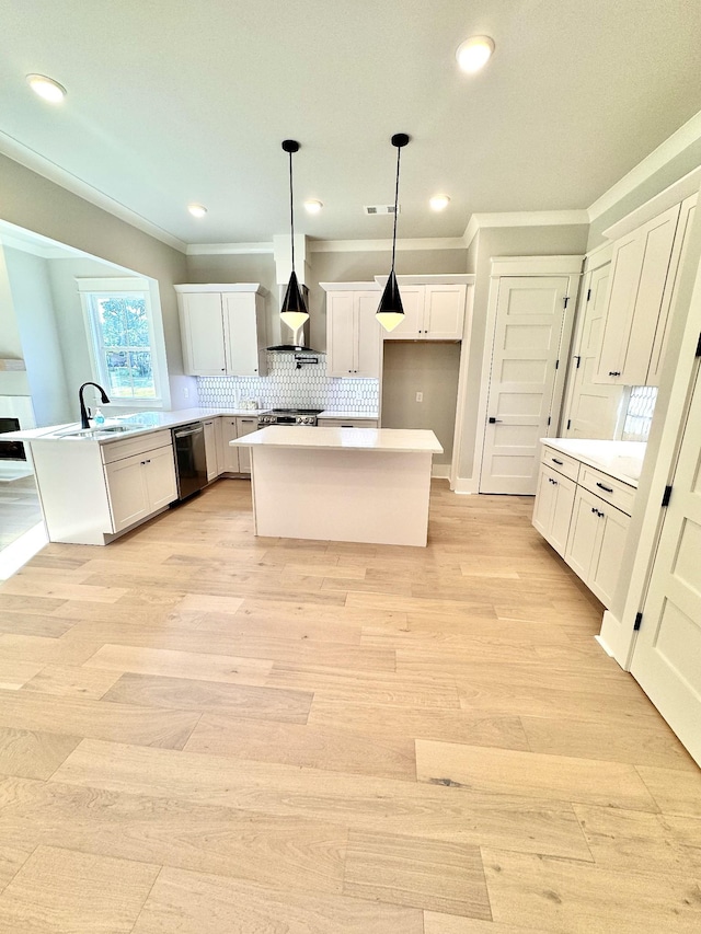 kitchen with a center island, hanging light fixtures, dishwasher, white cabinets, and wall chimney range hood