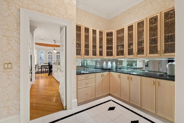 kitchen with dark countertops, wallpapered walls, glass insert cabinets, and light tile patterned flooring