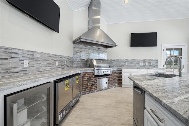 kitchen with beverage cooler, white cabinets, refrigerator, wall chimney range hood, and a sink