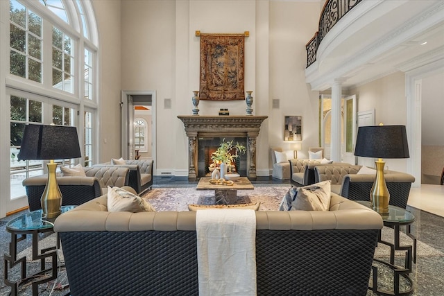 living room featuring baseboards, a high ceiling, a glass covered fireplace, and ornate columns