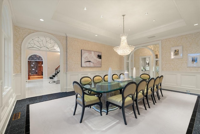 dining area featuring arched walkways, a wainscoted wall, visible vents, a raised ceiling, and wallpapered walls