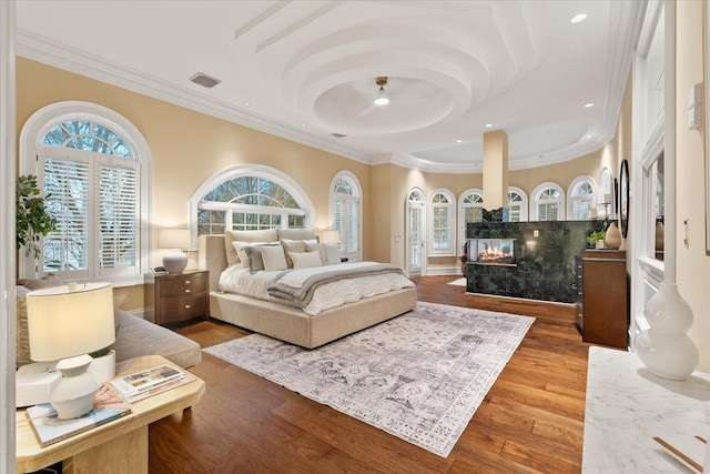 bedroom with visible vents, wood finished floors, crown molding, a multi sided fireplace, and recessed lighting