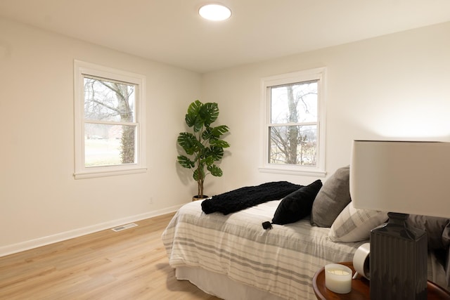 bedroom with multiple windows and light hardwood / wood-style flooring