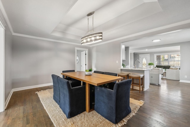 dining space featuring dark hardwood / wood-style floors, a raised ceiling, crown molding, and a chandelier