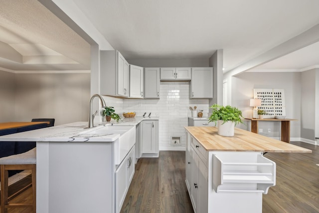 kitchen featuring light stone countertops, dark hardwood / wood-style floors, a kitchen bar, a kitchen island, and ornamental molding