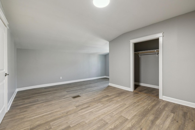 unfurnished bedroom with dark hardwood / wood-style floors, a closet, and lofted ceiling