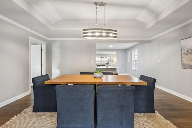 dining area featuring an inviting chandelier, crown molding, dark wood-type flooring, and a tray ceiling