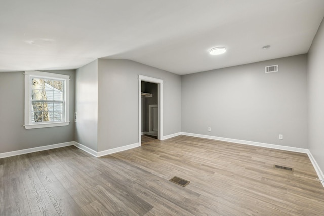 empty room featuring light hardwood / wood-style floors and vaulted ceiling