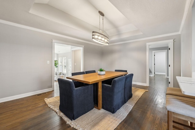 dining area featuring dark wood-type flooring, an inviting chandelier, a raised ceiling, crown molding, and a textured ceiling