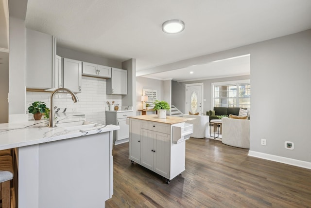 kitchen featuring white cabinetry, dark hardwood / wood-style flooring, a kitchen island, and sink